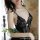 A woman wearing a black lace lingerie set, featuring delicate floral patterns and thin straps, holding white roses.