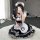 A person wearing a black and white maid costume with a cat paw design, sitting on a fluffy rug while taking a selfie.