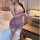 A woman wears a purple sheer cheongsam with traditional knotted buttons, holding a cup while seated on a bed. the outfit feat...