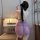A woman stands facing away from the camera, wearing a purple sheer cheongsam with butterfly designs and traditional knotted b...