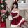 A woman poses beside a christmas tree wearing a festive red dress with white trim, bunny ears, and stockings, holding a gift ...