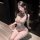 Woman wearing chaomu sheer mesh bodysuit with lace trim, fishnet stockings, and blindfold in a dimly lit room.