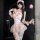 Woman modeling pink chaomu sensual lingerie set with lace, pearls, and feather wand in elegant boudoir style.