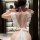 Woman wearing white cherry romance lingerie dress with lace details, bow back, and maid-style headpiece in elegant room setti...