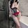Woman in bathroom wearing red and black cherry romance lingerie set with sheer bodysuit and short skirt for date night.