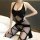 Woman wearing cherry romance sheer open-crotch bodysuit with black fishnet stockings, posing on bed.