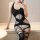 Woman wearing black sheer bodysuit with cutouts and fishnet stockings, sitting on a bench.