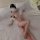 Woman wearing a pink sheer chiffon chinese style doudou bralette and vintage lingerie set on a white bed.