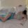 Woman in bed wearing sheer blue chinese style doudou bralette with floral embroidery and feather fan.