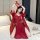 A woman poses on a bed wearing a red chinese-style hanfu bodice sleep dress made of sheer chiffon, featuring intricate patter...