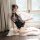 A woman poses on a fluffy rug wearing a black floral halter bodysuit, featuring a retro design and modernized sexy elements, ...