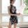 A woman stands by a window wearing a floral halter bodysuit, holding a feather fan. the dress features a retro design with mo...