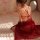A woman sits gracefully wearing a red chinese-style sexy hanfu lingerie set, featuring traditional silk doudou sleepwear, per...