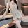 Woman wearing a white sheer lace cheongsam lingerie set with long sleeves and matching thigh-high stockings in a modern hotel...