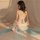 A woman models a sheer chiffon vintage lingerie set, featuring a delicate bralette with crisscross straps and flowing fabric,...