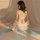 A woman sits facing away from the camera, wearing a sheer chiffon chinese traditional doudou lingerie set. the outfit feature...