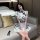A woman sits on a couch wearing a white chinese new year-themed dress inspired by a qipao, featuring black floral patterns an...