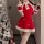 A woman poses with a christmas tree adorned with ornaments, wearing a festive red dress featuring white fur trim and snowflak...