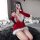A person poses with a phone, wearing a festive red dress featuring white fur trim and cat ears. the outfit includes long glov...