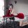 A person poses playfully on a chair wearing a festive christmas-themed sleepwear set, featuring a red mini skirt with white f...