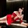 A woman poses in a festive christmas red velvet babydoll dress set, featuring lace details and bow hair accessories, embodyin...