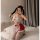 A woman poses playfully wearing a red bunny girl cosplay maid outfit, featuring a white ruffled top and skirt with matching a...
