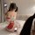 A woman poses playfully wearing a red bunny-themed cosplay maid outfit, featuring a cute design with ruffles and a bow, perfe...