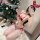 A woman poses in a festive setting, wearing a red christmas-themed bikini set with lace and faux fur balls. the outfit featur...