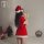 A woman wearing a festive red velvet christmas sleep dress with white trim, complete with a santa hat, taking a selfie indoor...
