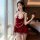 Woman wearing red christmas vintage velvet lace deep v sexy sleep dress with pearl belt, posing by window in bedroom.