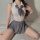 A woman wears a college-style backless lingerie dress, featuring a white top with a gray tie-front and pleated skirt, creatin...