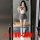 Woman in mirror wearing backless jk uniform bodysuit with bow, pleated skirt, and striped knee-high socks.