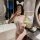 Woman in white lace lingerie pajamas with bow and bunny ears, taking a mirror selfie in a luxurious bedroom setting.