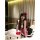 A woman poses with a hello kitty plush toy wearing a cute maid costume set featuring a black and white dress with a red bow h...