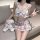 Woman wearing cute plaid jk skirt outfit with lace-up hollow top, holding teddy bear on sofa.