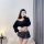 A woman poses with a phone featuring a cute bear case, wearing a black sheer sweater and a plaid micro skirt, showcasing a pl...