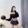A woman poses with a balloon, wearing a black off-shoulder sweater and a plaid mini skirt, showcasing a cute schoolgirl-inspi...