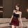 Woman modeling dark romance lace bodysuit with sheer mesh and red rose details, paired with a burgundy skirt.