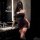 Woman in dark romance lace mesh cheongsam set with sheer rose-embellished halter corset and high-waisted thong bodysuit.