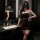 Woman in dark romance lace mesh cheongsam set with sheer rose-embellished halter corset and high-waisted thong bodysuit.