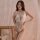 A woman poses elegantly in a white deep v lace open-crotch sexy lingerie set, featuring intricate lace details and a plunging...