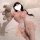 Woman in pink domila maid lingerie with lace and ruffles, holding a teddy bear on a bed.