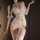 Woman wearing white domila lace sheer sleep dress with deep v-neck, open-crotch design, and garter straps.