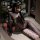 Woman wearing domoila irregular mesh sheer leopard bodysuit with backless lace-up design, posing in front of christmas tree.