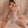 A woman poses in a sheer halter bodysuit with lace detailing, featuring delicate hearts and red accents, perfect for a sensua...