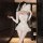 Woman wearing dreamy bridal lingerie set with lace, sheer mesh, garters, veil, and fan in elegant room.