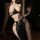 Woman wearing egyptian cat lady costume - sexy hollow-out halter gown, holding a bottle in dim lighting.