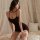 Woman wearing elegant black satin slip dress, posing on bed with soft lighting — perfect for boudoir or date night allure.