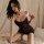 Woman in elegant black satin slip dress posing on bed, showcasing sexy chemise style for boudoir or date night wear.