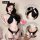 Model wearing black lace halter top and matching strappy bottoms with cat ears, featuring crisscross straps and decorative ta...